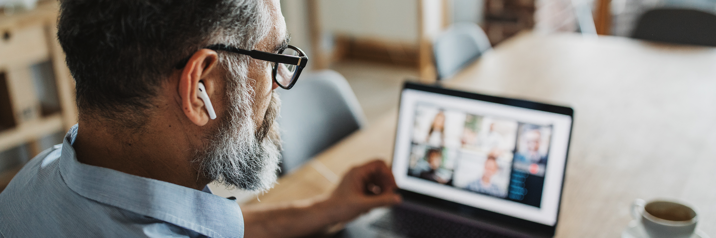 Ein Mann mit Brille und Kopfhörern sitzt vor einem Laptop am Tisch