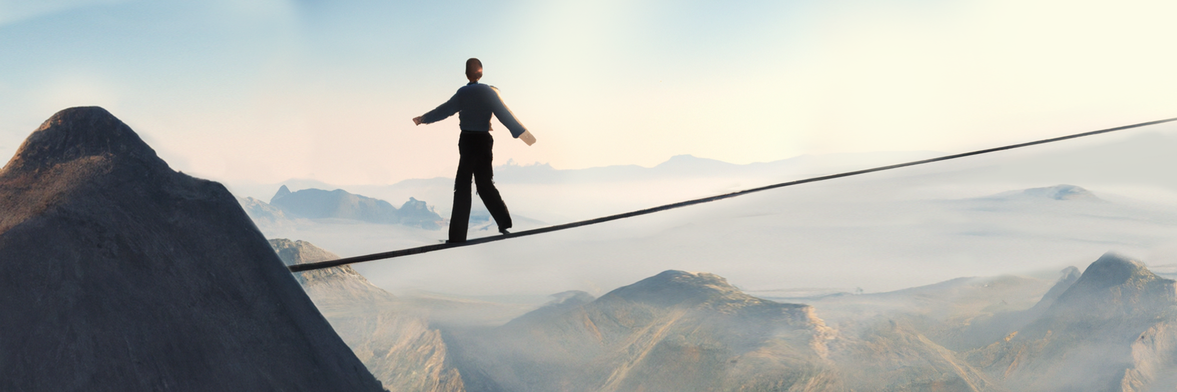 Ein Mensch balanciert auf einem Seil, dass zwischen Bergen gespannt ist
